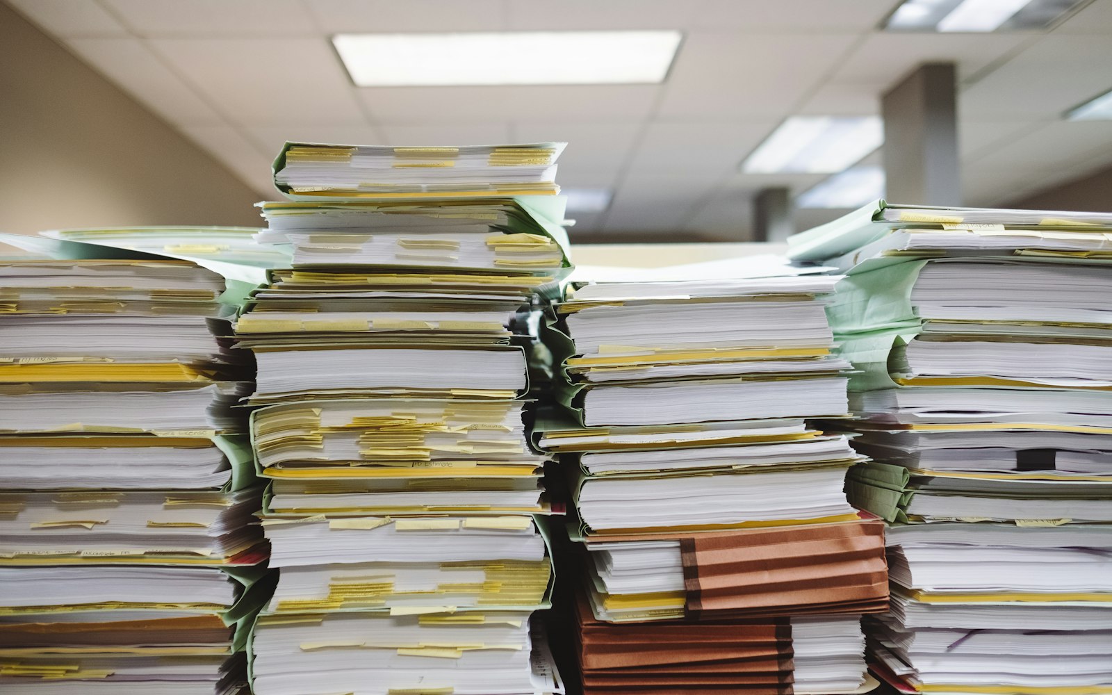 Stacks of business documents and file folders containing personal data
