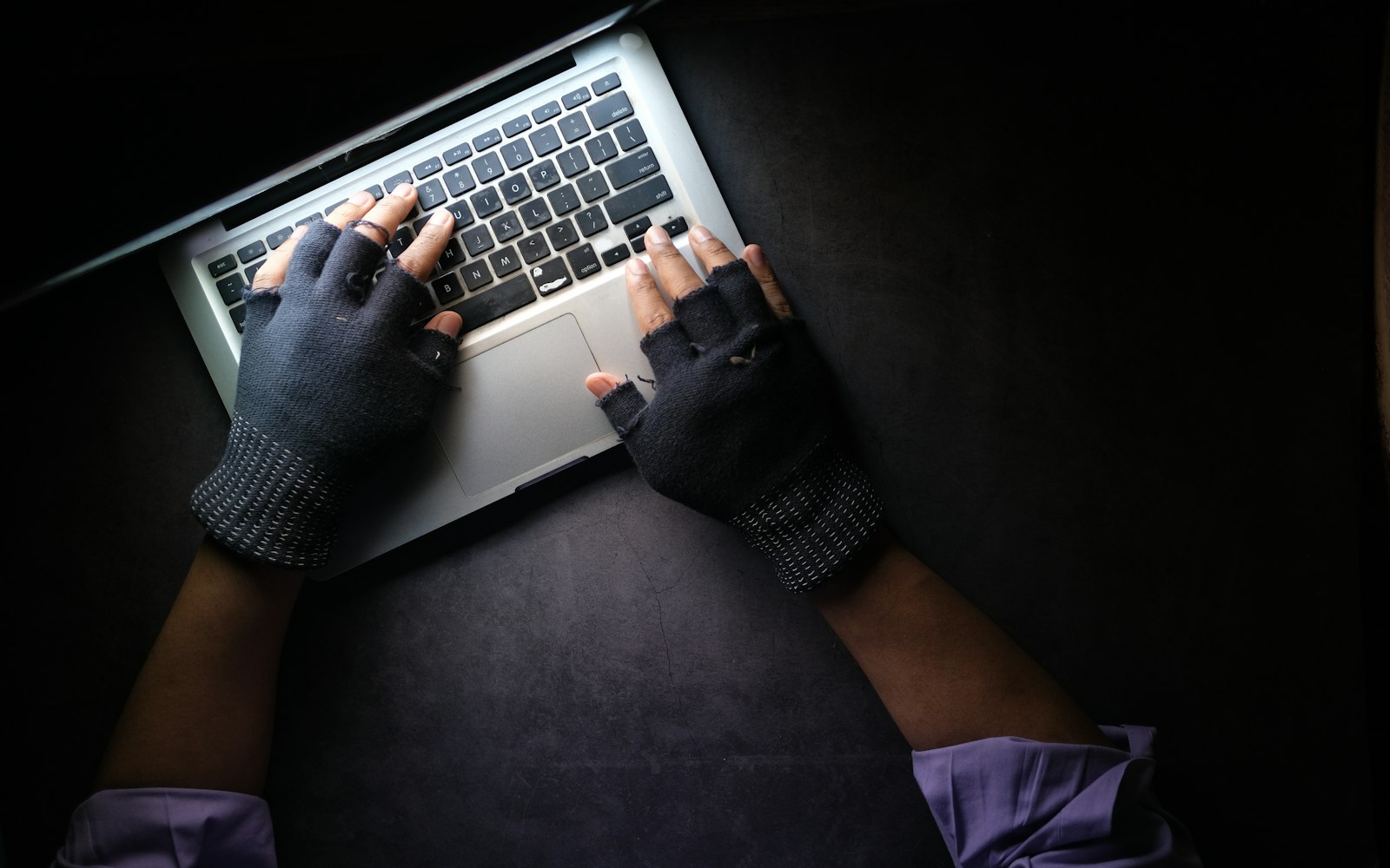Person typing on a laptop in a dark setting, as in a phishing attempt